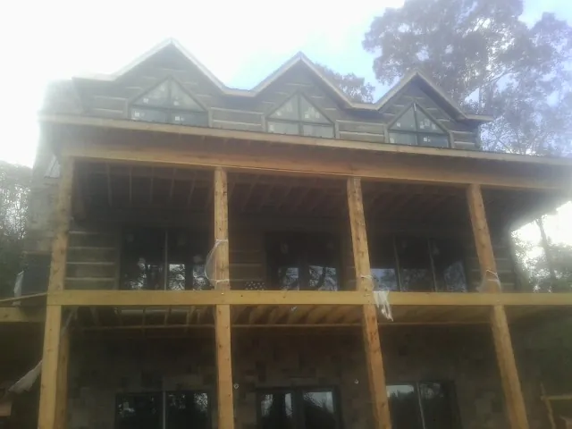 Dormers and porch framing on a large log home under construction — Roof Coating work by our crew in Dameron